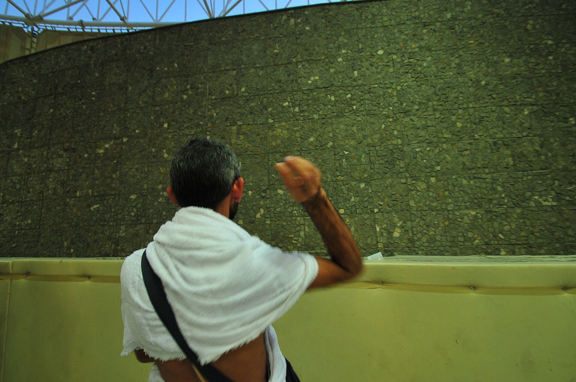 A pilgrim in ihram performs the stoning ritual at the Jamarat in Mina during Hajj — the same valley where Saudi Arabia hosted families of its war dead in specially equipped camps in 2026