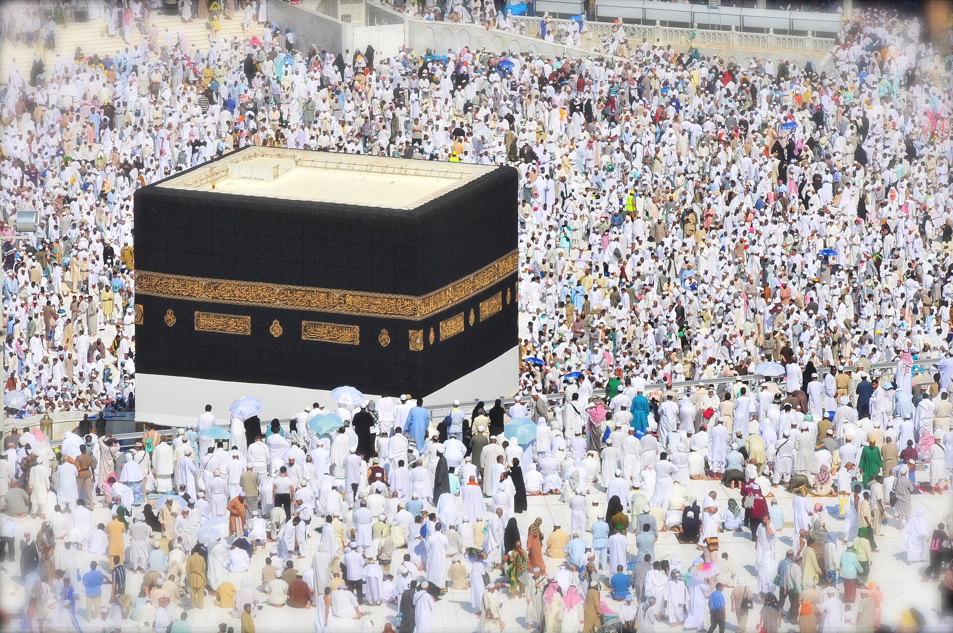 Muslim pilgrims in white ihram garments circumambulate the Kaaba at the Grand Mosque in Mecca during Hajj — the pilgrimage whose rites define Saudi Arabia's governing legitimacy as Custodian of the Two Holy Mosques