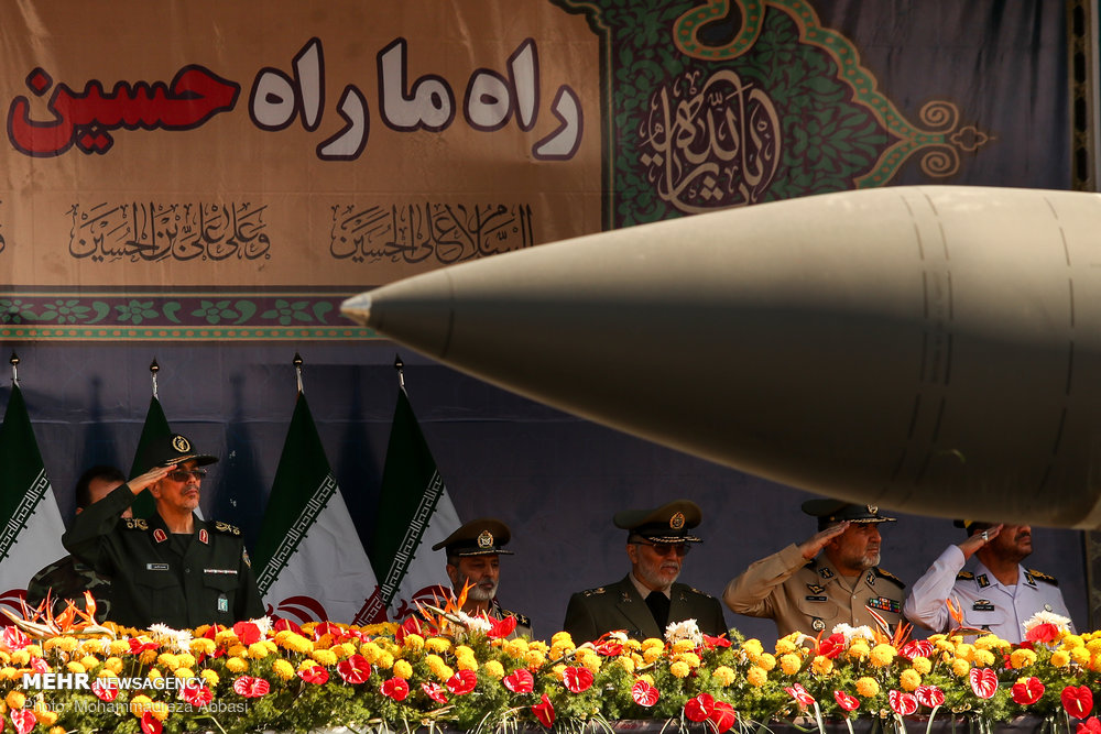Iranian military commanders salute as a ballistic missile passes at the 2018 Sacred Defence Week parade in Tehran, illustrating IRGC command structure and missile capability
