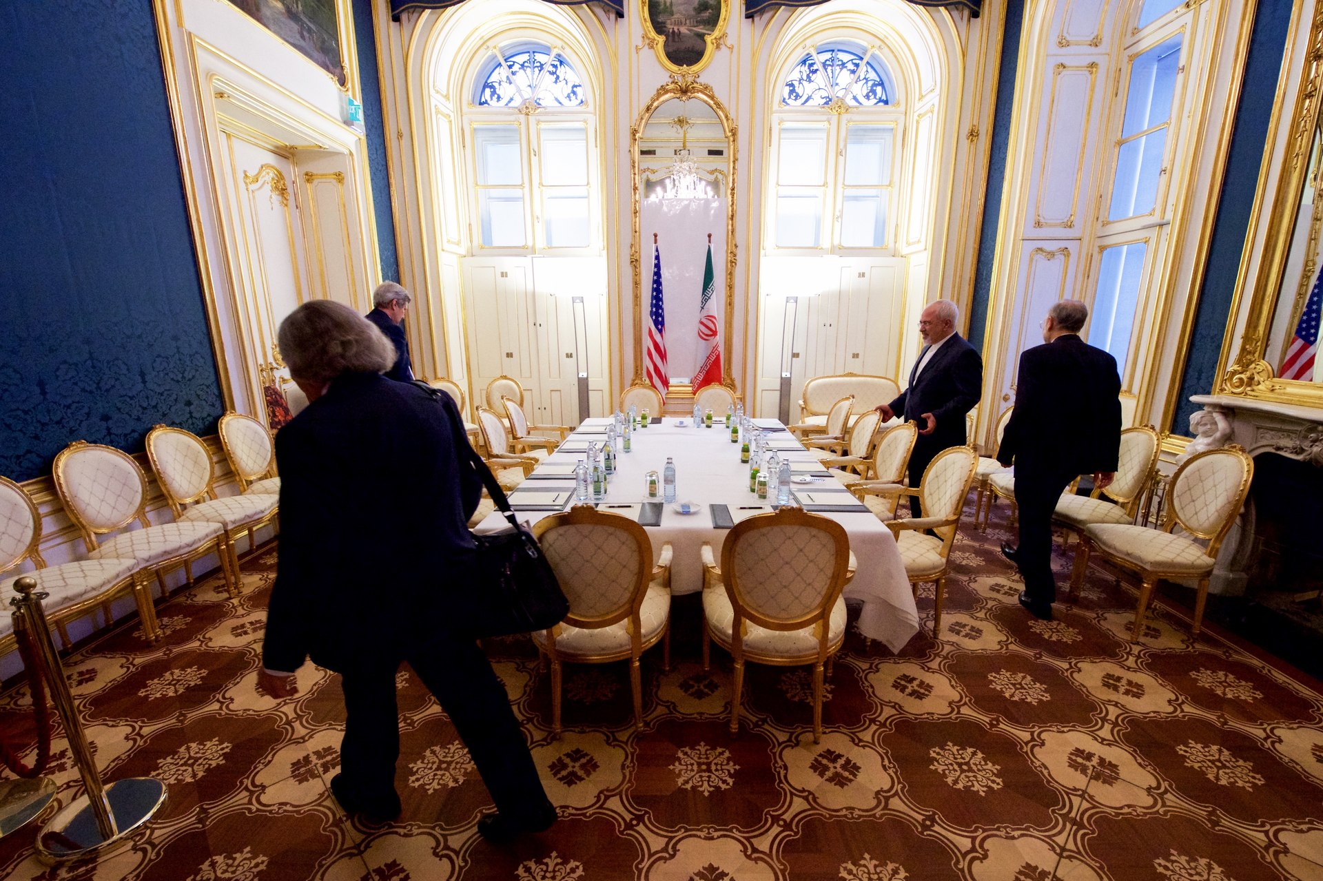 US Secretary of State John Kerry and Energy Secretary Ernest Moniz at the Iran nuclear negotiations table in Vienna, 2015, with US and Iranian flags
