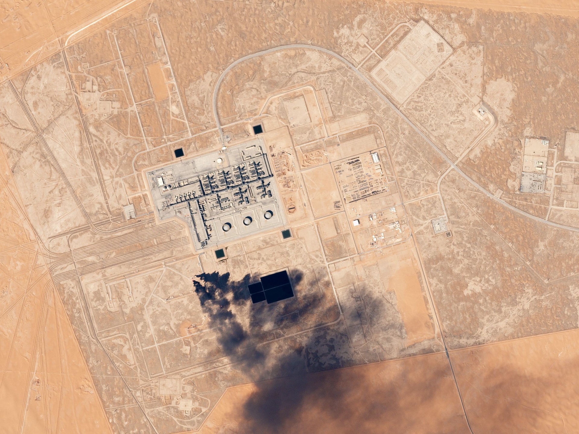 Satellite image of Khurais oil processing facility in Saudi Arabia desert showing smoke plume from infrastructure damage, Planet Labs 2017
