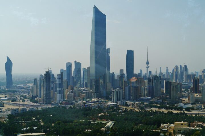 Kuwait City skyline showing the al-Hamra Tower and Kuwait Liberation Tower — the city has absorbed 265 ballistic missile intercepts since February 28 and filed a UN Charter Article 51 self-defense claim alone, without a single GCC partner