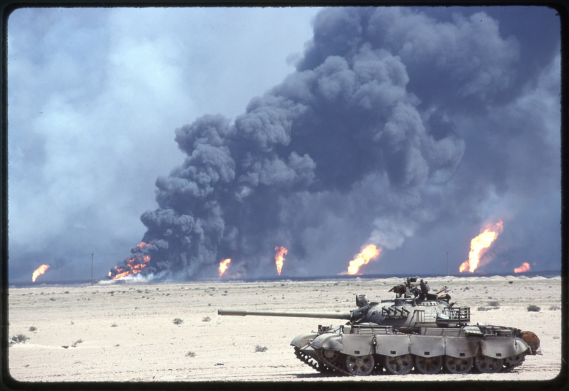 Destroyed Iraqi tank in foreground with Kuwait oil well fires burning on the horizon, Desert Storm 1991, the precedent for UN Compensation Commission reparations