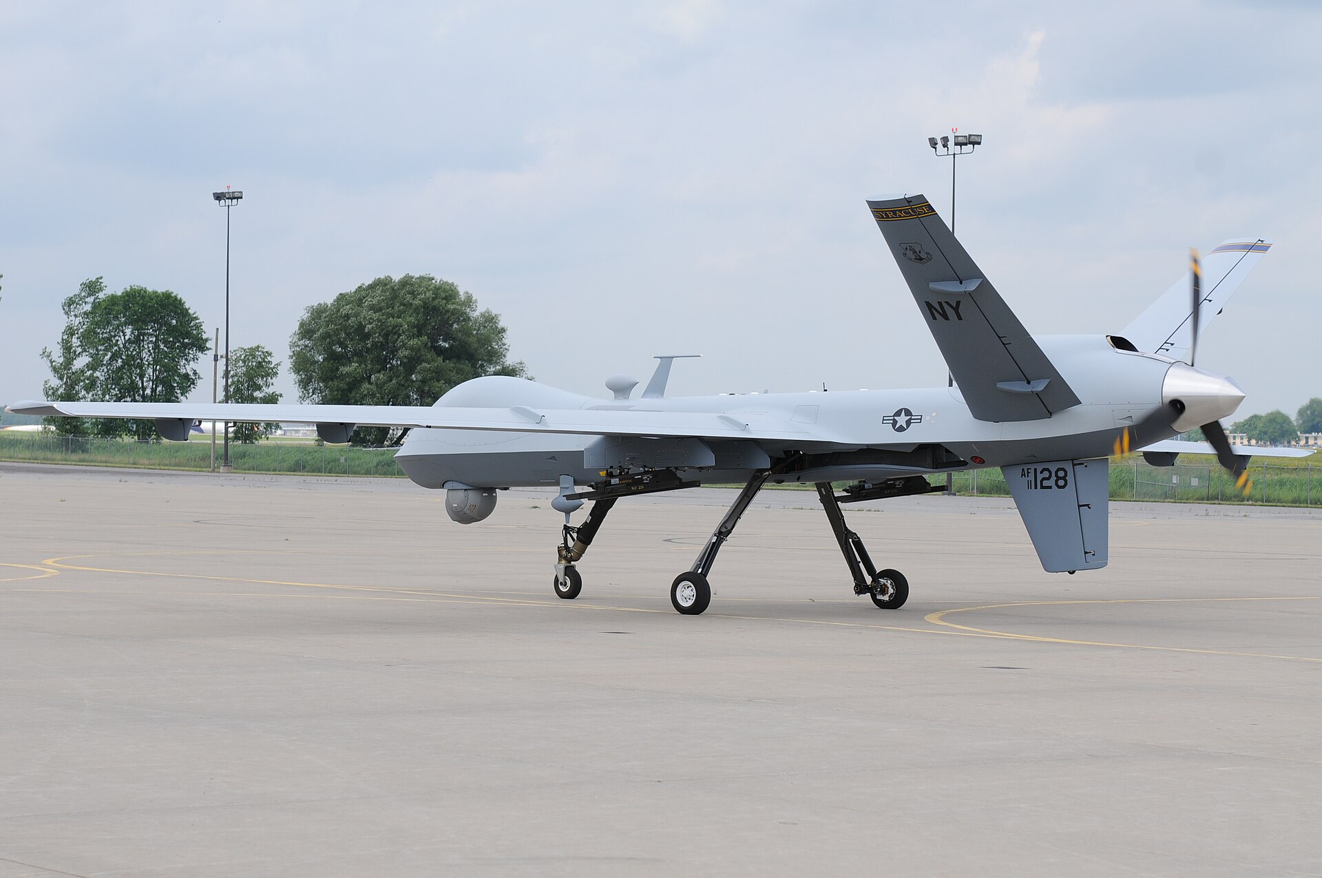 An MQ-9 Reaper unmanned aircraft sits on the flight line at an Air National Guard base, showing the full wingspan and weapons pylons of the $50 million surveillance and strike drone