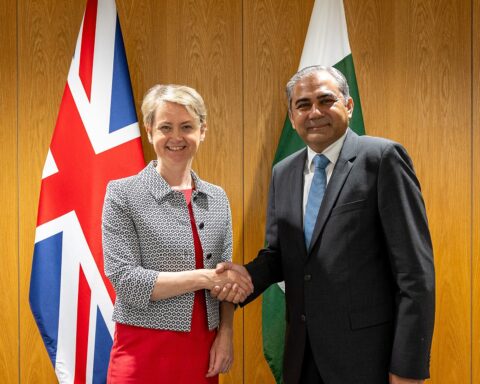Pakistan Interior Minister Mohsin Naqvi shakes hands with UK Home Secretary Yvette Cooper in London, August 2024, in front of Pakistani and UK flags