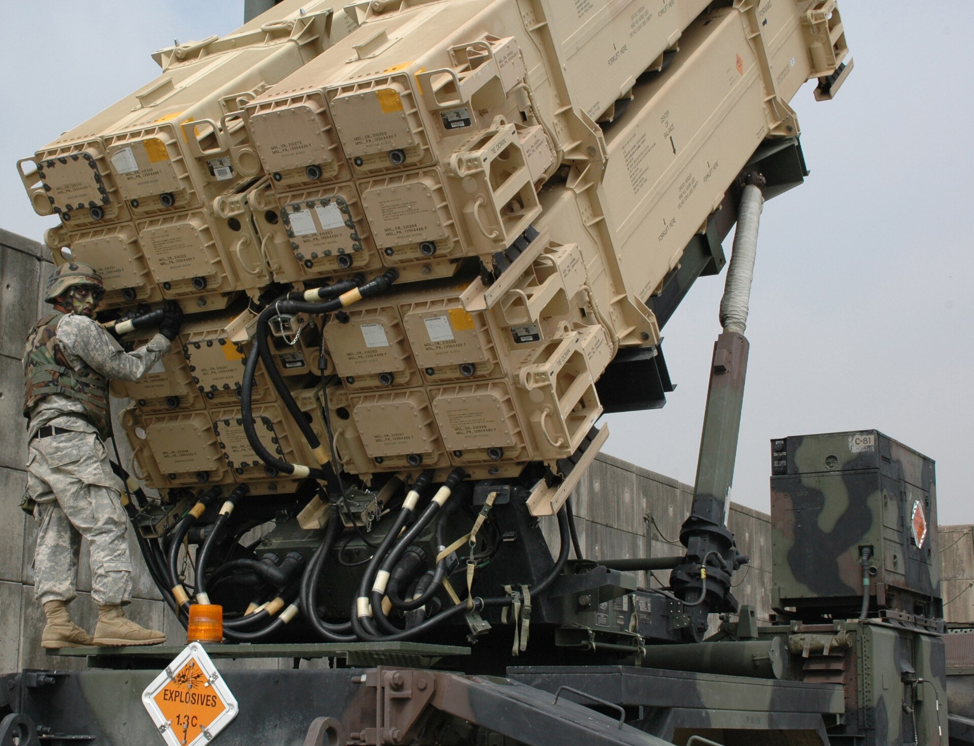 US Army soldier performs maintenance on a PAC-3 MSE Patriot missile launcher, showing the sealed interceptor canisters of the terminal-phase air defense system
