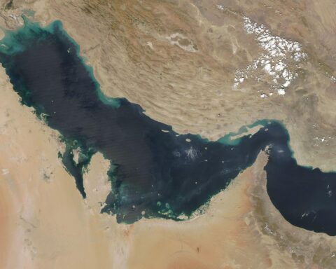 NASA MODIS true-color satellite image of the Persian Gulf, showing Iran to the north and the Arabian Peninsula to the south, with the Strait of Hormuz visible at right