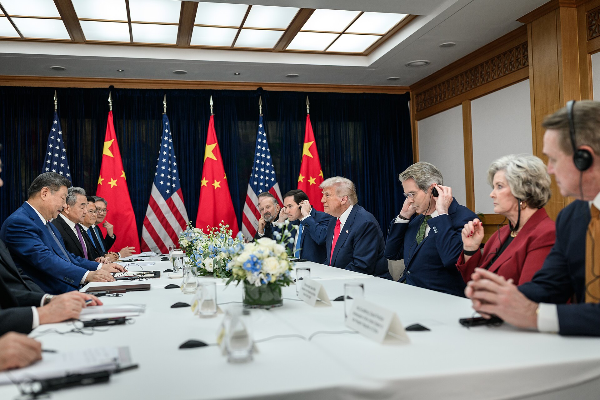 President Trump and Xi Jinping at their bilateral meeting at Gimhae International Airport, Busan, South Korea, October 30, 2025, with US and Chinese flags displayed. White House Photo by Daniel Torok / Public Domain.