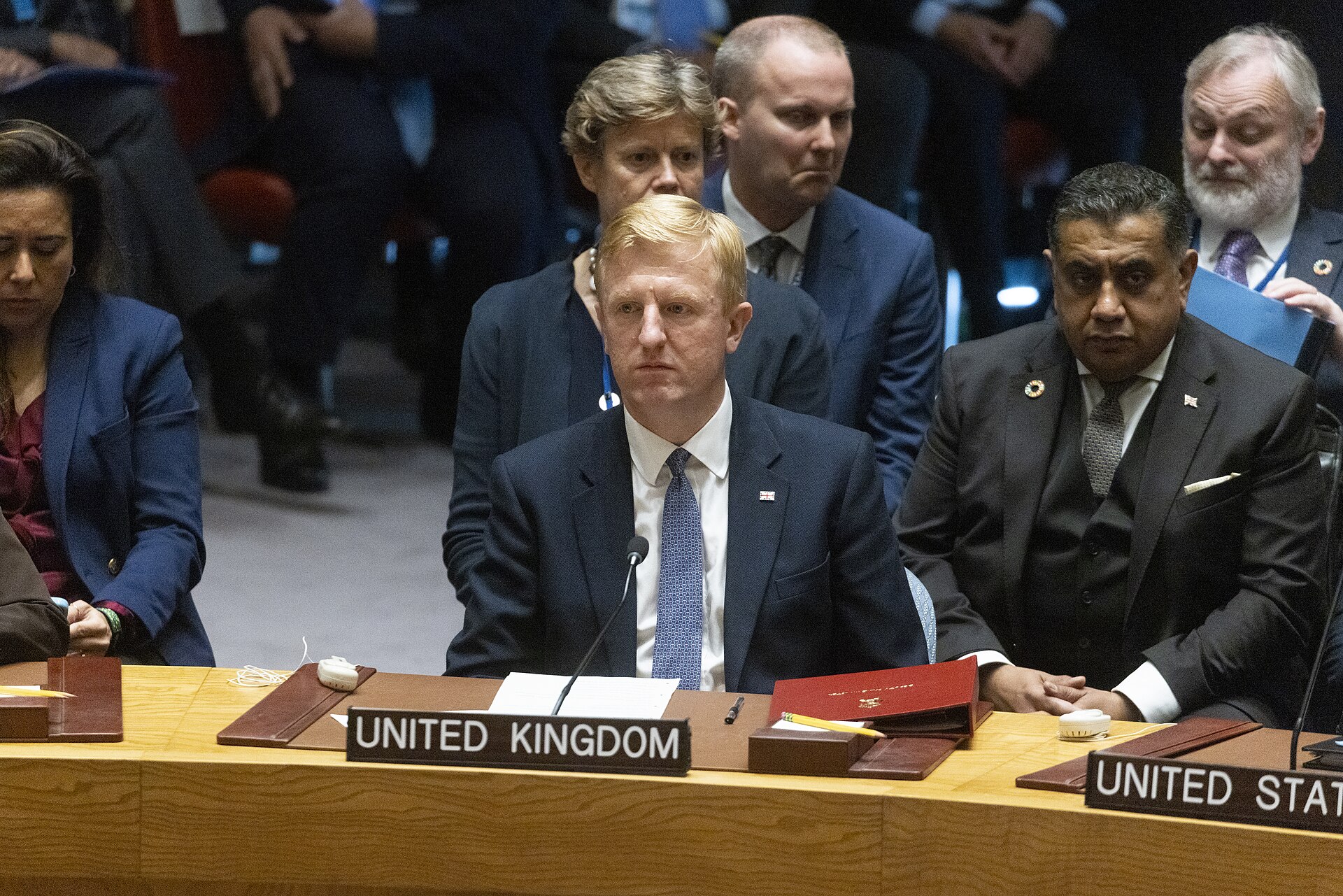 UN Security Council horseshoe chamber during an open debate, with delegations from the United Kingdom and United States seated at the table
