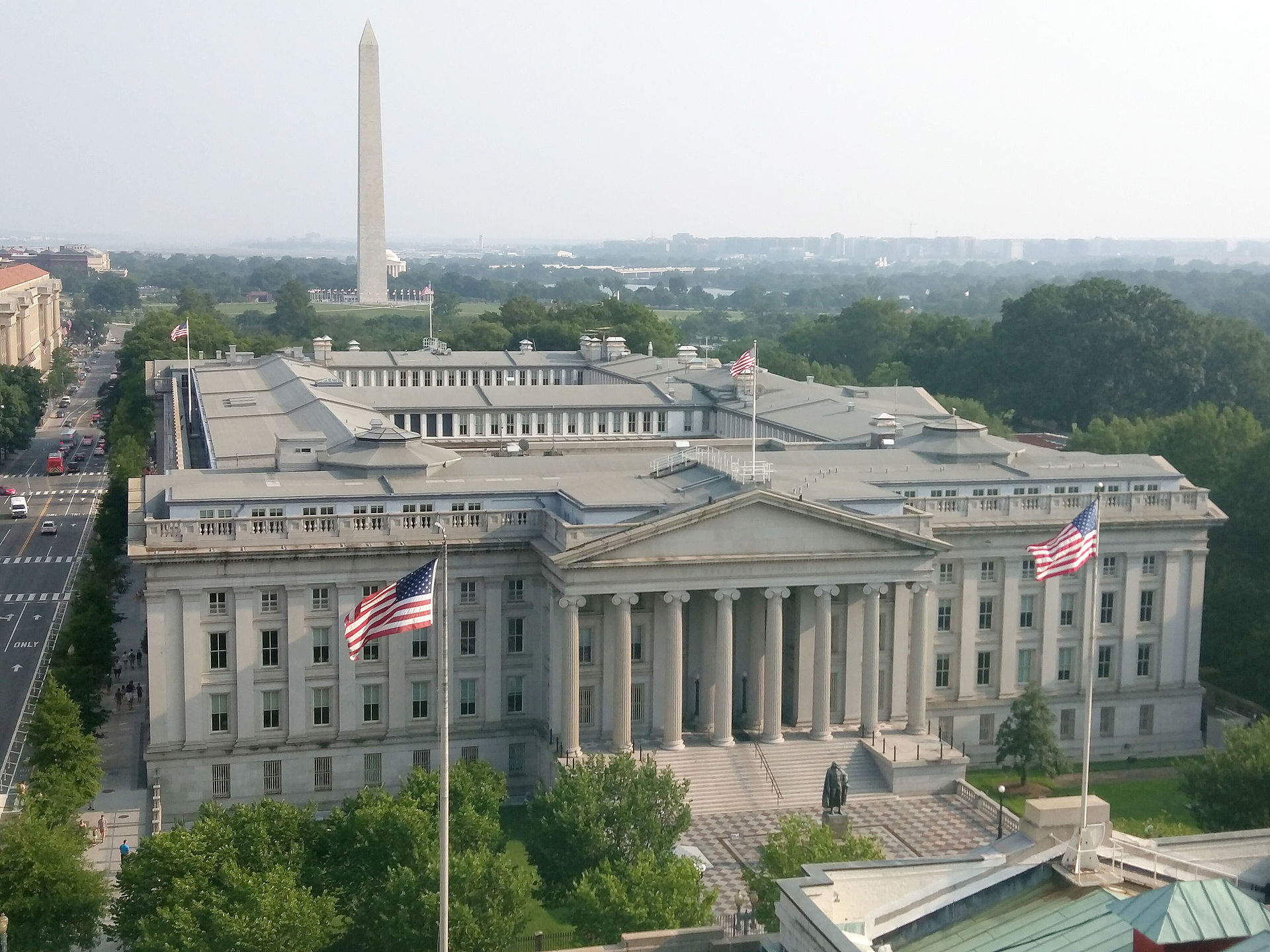 US Treasury Department building Washington DC with American flags and Washington Monument in background