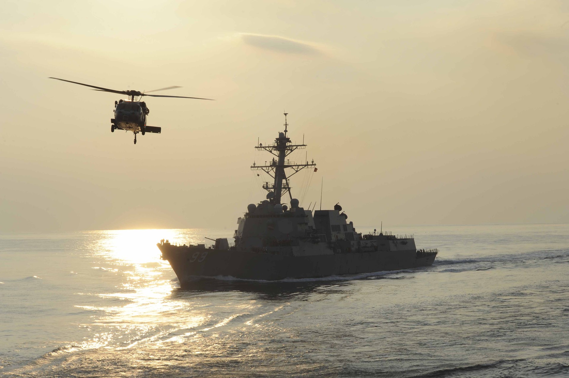 USS Farragut (DDG 99), an Arleigh Burke-class guided-missile destroyer, underway in the Arabian Sea with an MH-60S Sea Hawk helicopter — the type of escort asset deployed in Project Freedom