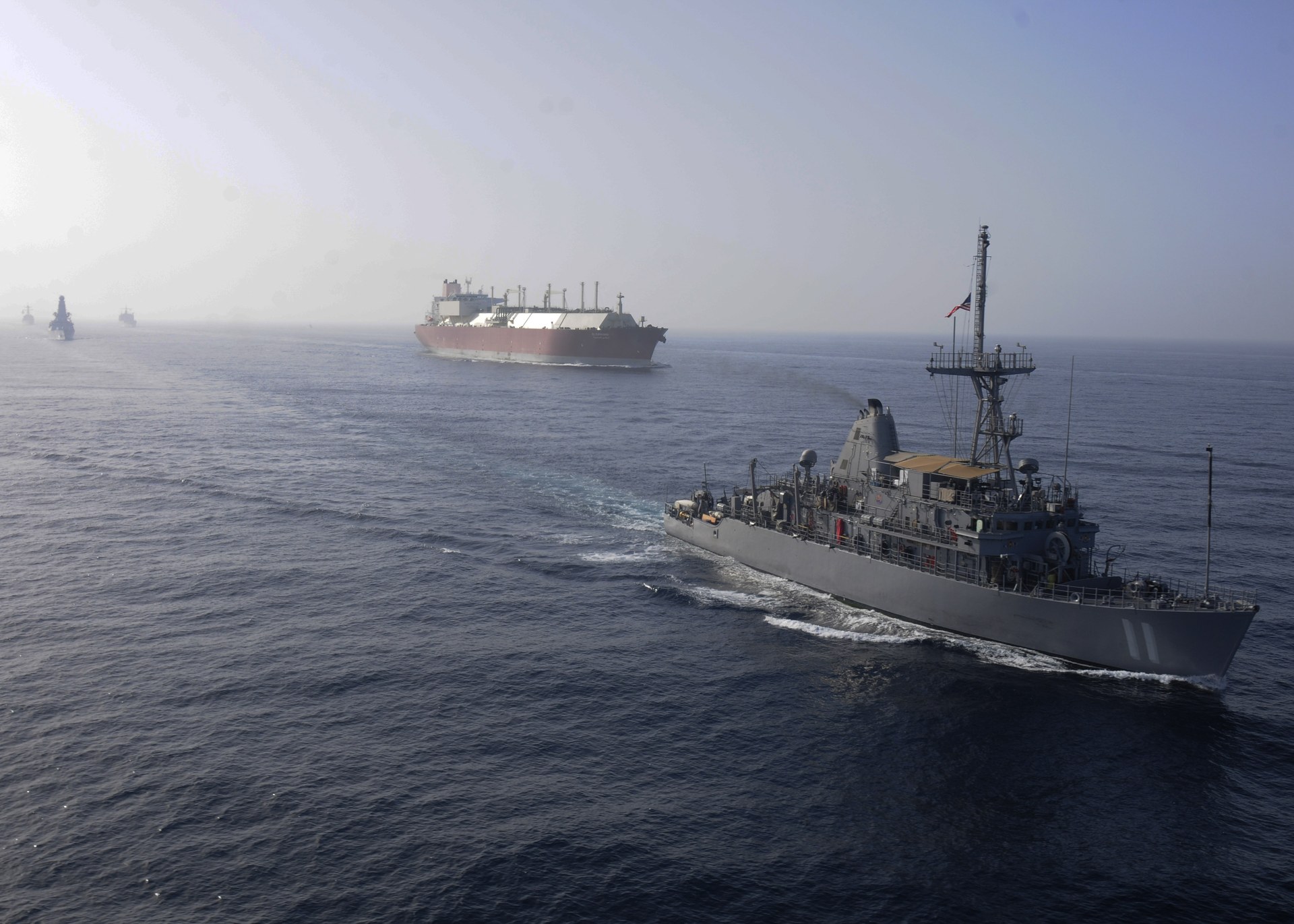 USS Gladiator MCM-11, an Avenger-class mine countermeasures ship, conducts convoy escort operations with a large LNG tanker in the Persian Gulf during International Mine Countermeasures Exercise 2013