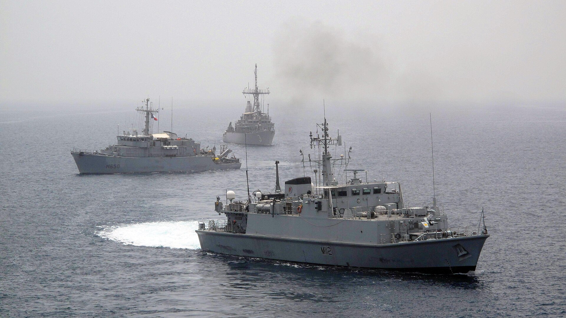 French, US, and Royal Navy mine countermeasures vessels in formation in the Persian Gulf during IMCMEX 2013 — the same allied coalition now deployed for Hormuz clearance operations in 2026.