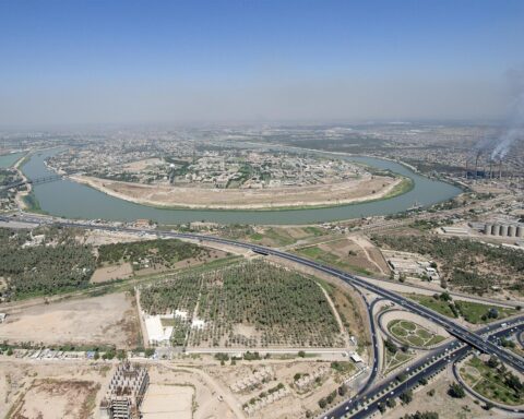 Aerial view of Baghdad with the Tigris River curving through the city — Iraq's capital where FM Fuad Hussein issued the eight-party regional security summit invitation on June 28, 2026