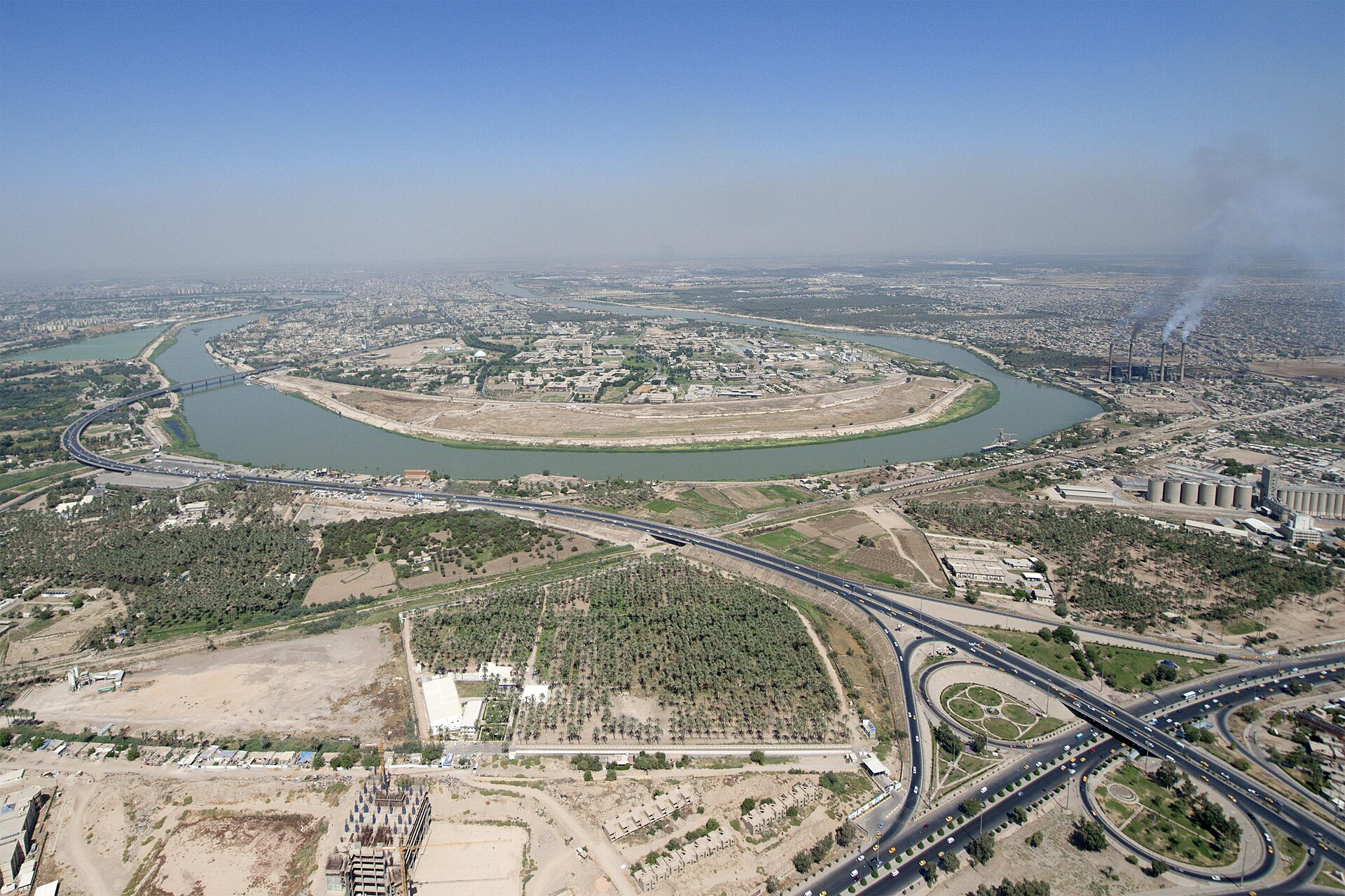 Aerial view of Baghdad with the Tigris River curving through the city — Iraq's capital where FM Fuad Hussein issued the eight-party regional security summit invitation on June 28, 2026