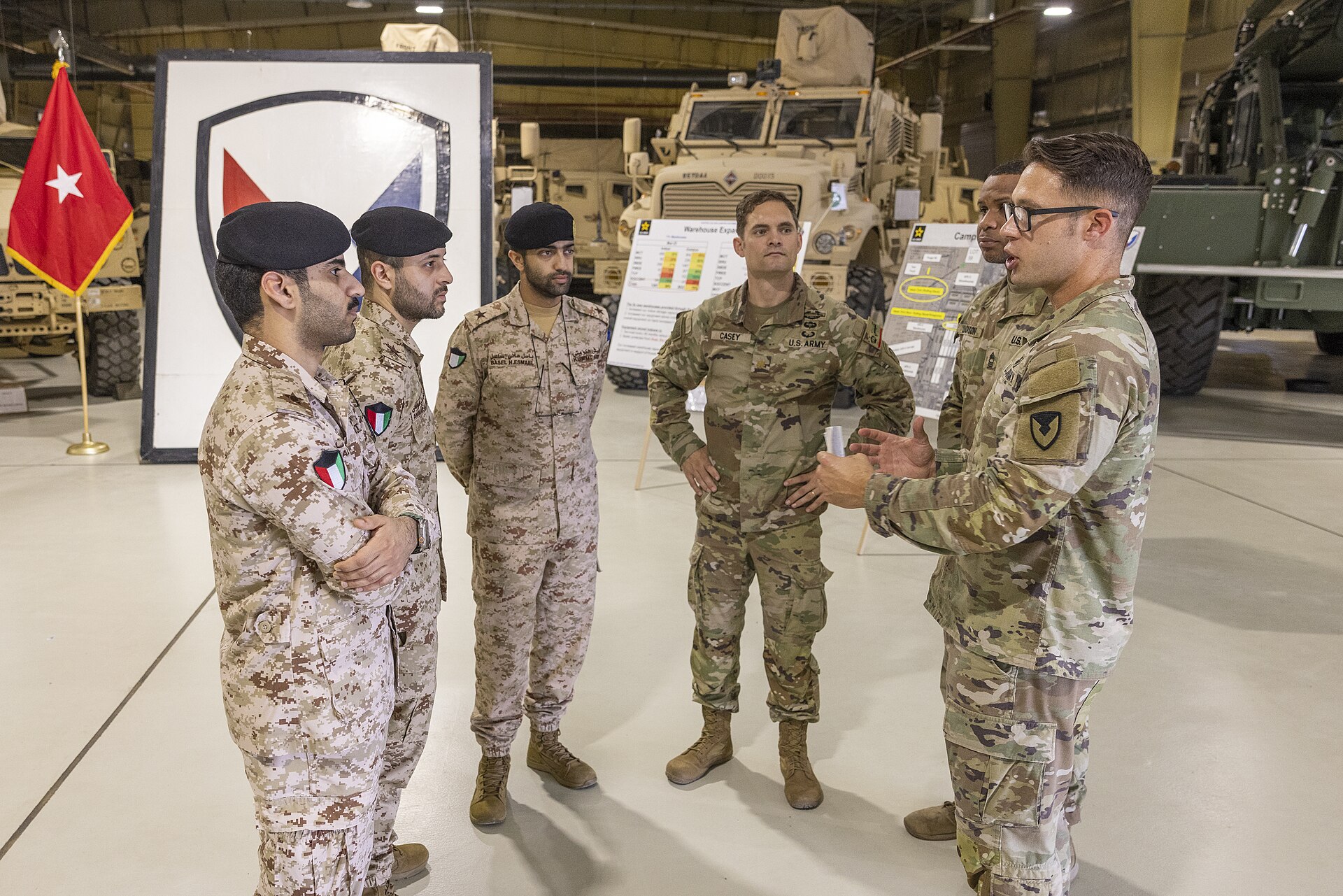US and Kuwaiti military officers briefed on Army Prepositioned Stock-5 in warehouse at Camp Arifjan, Kuwait, 2024