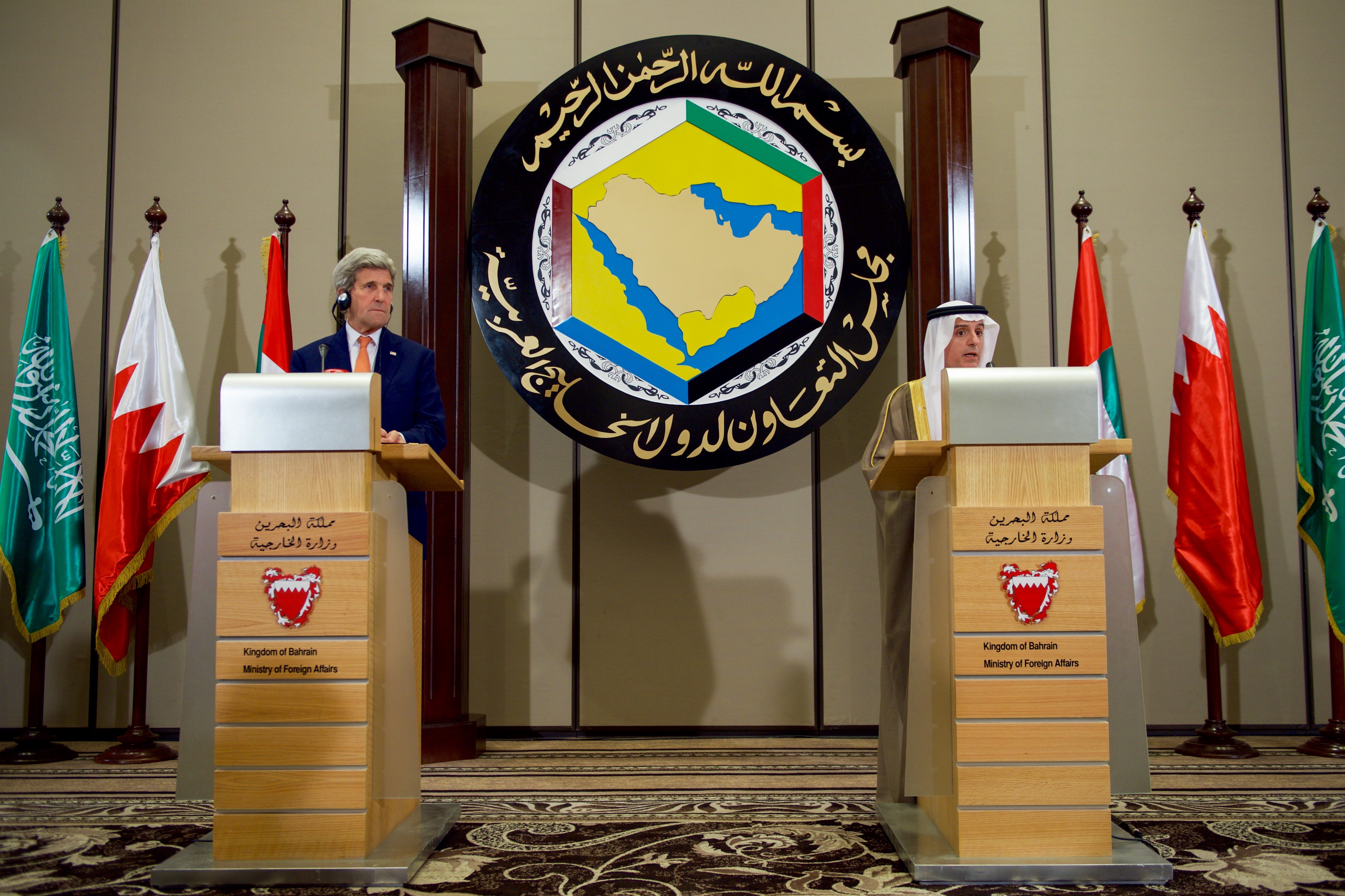 US Secretary of State Kerry and Saudi FM al-Jubeir at GCC Ministerial Meeting in Manama, Bahrain, with GCC emblem and member state flags