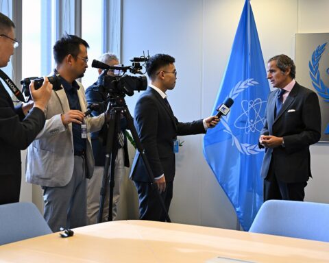 IAEA Director General Rafael Grossi being interviewed by Xinhua at the 68th IAEA General Conference in Vienna, September 2024, with the IAEA flag and logo visible behind him.