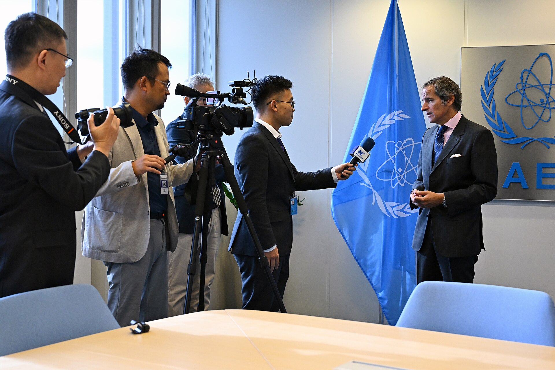 IAEA Director General Rafael Grossi being interviewed by Xinhua at the 68th IAEA General Conference in Vienna, September 2024, with the IAEA flag and logo visible behind him.