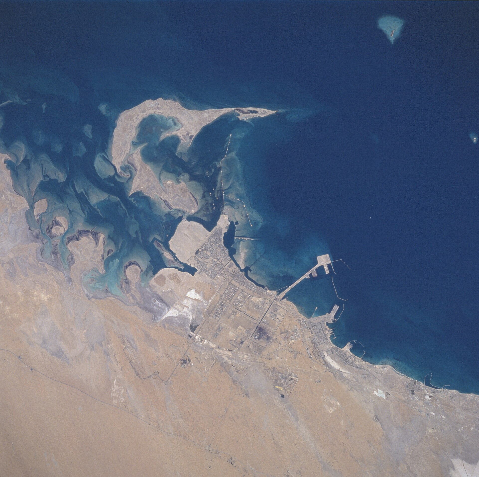 Jubail Industrial City, Saudi Arabia — aerial view from the Space Shuttle showing the petrochemical complex grid and King Fahd Industrial Port on the Persian Gulf coast, June 1996