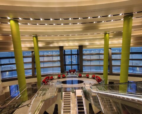 Interior of Kuwait International Airport Terminal 1 showing departure hall with escalators and glass facade overlooking the apron — the terminal struck by IRGC drones on June 3, 2026, forty-eight hours after reopening