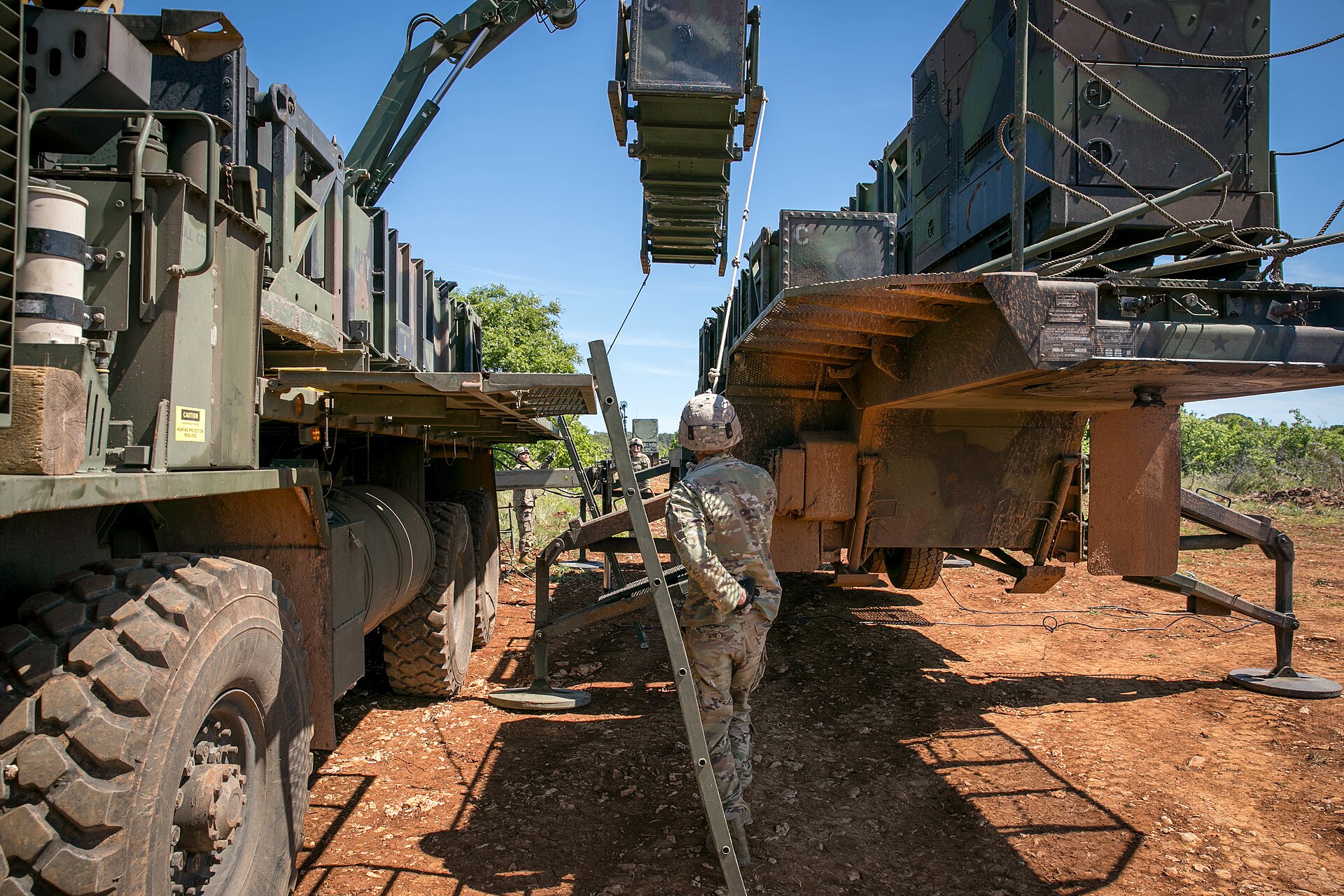 US Army soldiers load Patriot interceptor canisters onto a launching station during DEFENDER-Europe 21, illustrating the hands-on logistics chain that Camden must produce before delivery reaches any customer