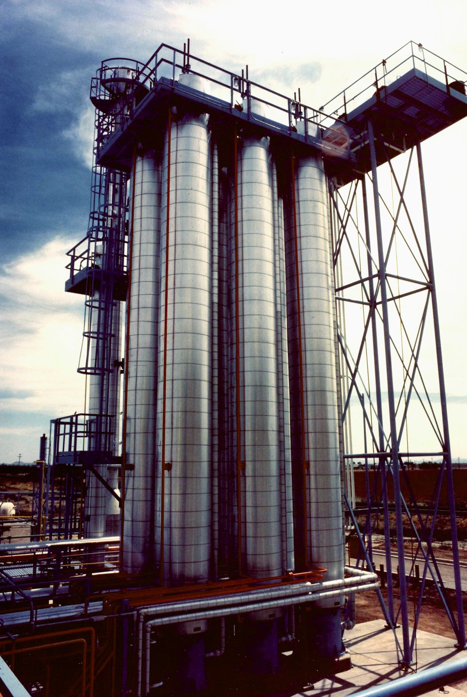 Large industrial chemical storage and processing columns at a petrochemical plant. Facilities producing TDI, MDI, and nitric acid use similar reactor column configurations.