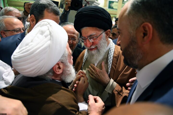 Hezbollah Secretary-General Naim Qassem (white turban) greets then-Supreme Leader Ali Khamenei at the 31st International Islamic Unity Conference, Tehran 2017 — the structural Hezbollah-Iran relationship that made his June 4 ceasefire rejection operationally significant