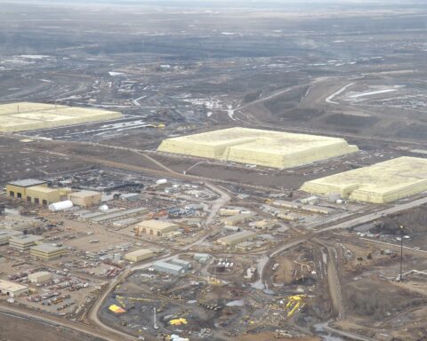 Aerial view of three massive yellow sulfur block pyramids at Syncrude base plant, Alberta Canada — industrial sulfur storage as byproduct of hydrocarbon processing