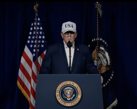 President Trump at a presidential podium announcing military action against Iran, February 28 2026, with US and presidential flags flanking him