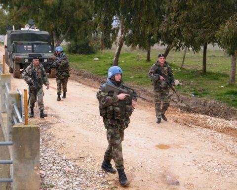 UNIFIL and Lebanese Armed Forces soldiers on joint patrol along the Blue Line in southern Lebanon, with military vehicle behind them
