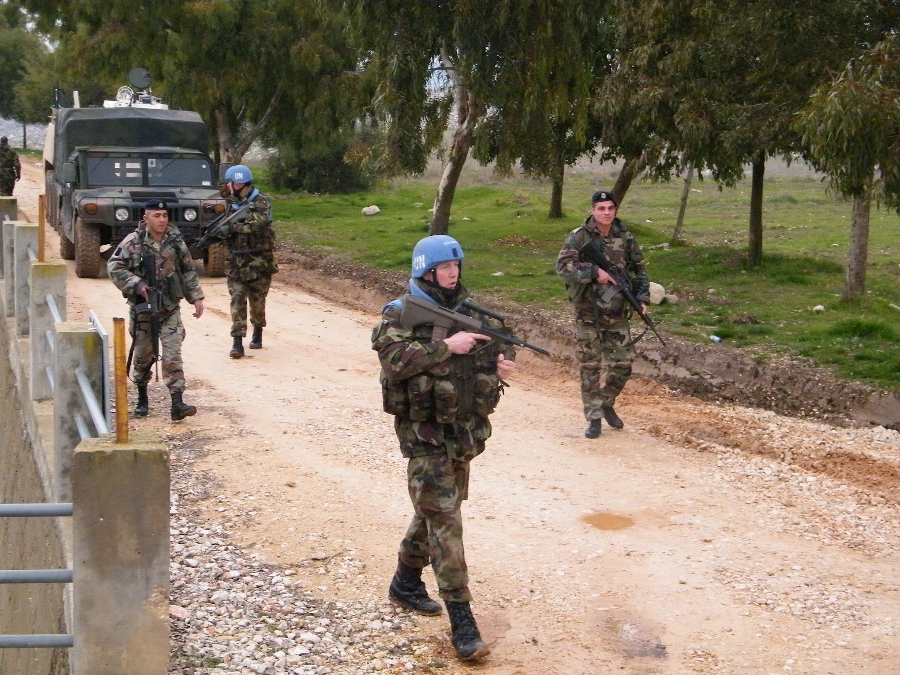 UNIFIL and Lebanese Armed Forces soldiers on joint patrol along the Blue Line in southern Lebanon, with military vehicle behind them
