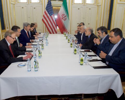 American and Iranian diplomatic delegations face each other across a negotiating table in Vienna, January 16 2016, with US and Iranian flags visible in background