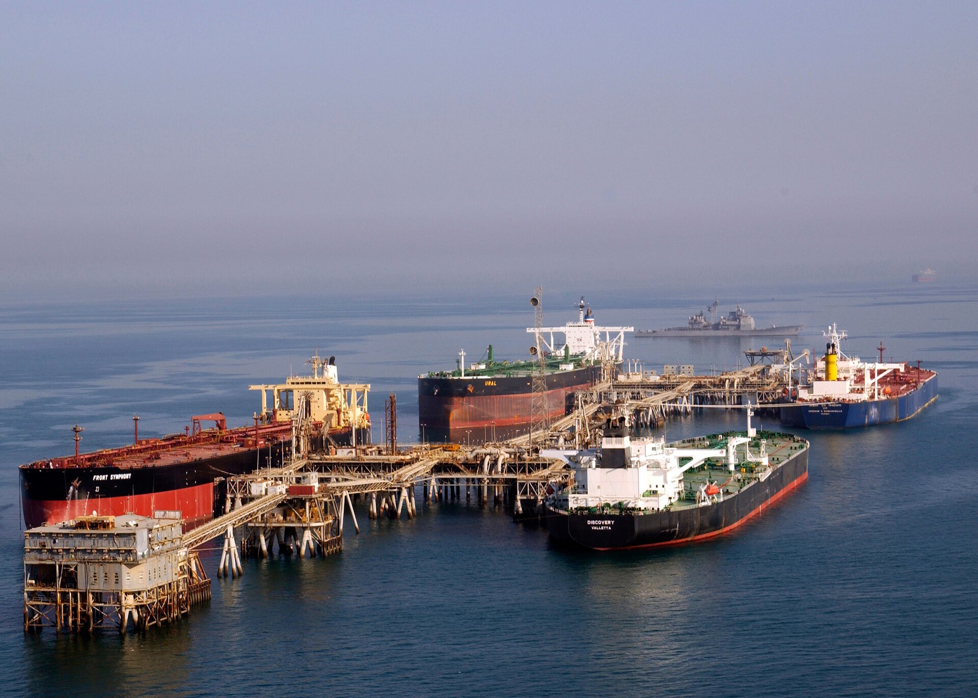 Multiple crude oil tankers loading at Arabian Gulf offshore terminal, with US Navy escort vessel