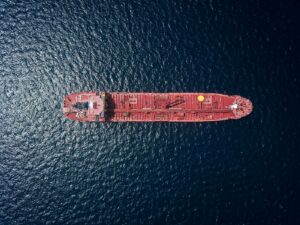 Aerial drone view of a red crude oil tanker crossing open sea, illustrating the global crude export routes at the centre of Aramco Arab Light OSP pricing decisions