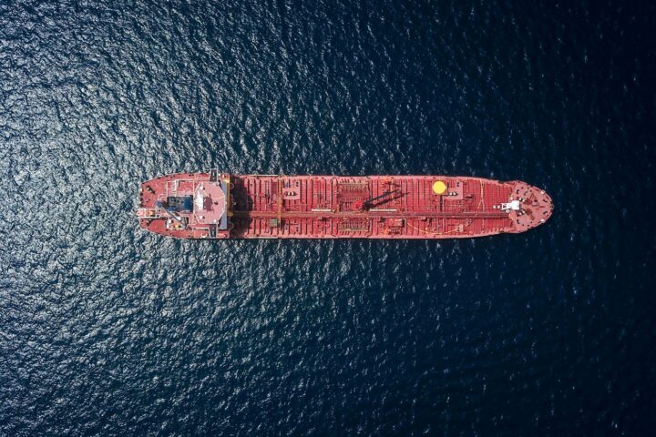 Aerial drone view of a red crude oil tanker crossing open sea, illustrating the global crude export routes at the centre of Aramco Arab Light OSP pricing decisions