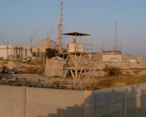 Bushehr Nuclear Power Plant, Iran — the reactor dome visible behind the concrete perimeter wall and guard tower, photographed by the IAEA