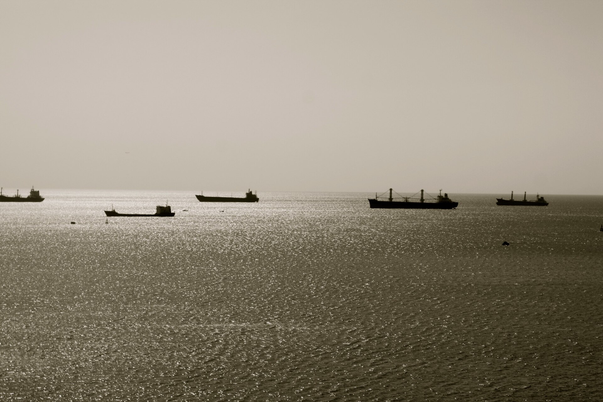 Cargo vessels at sea at sunrise — Red Sea transit traffic was already 50% below 2023 baseline before the July 2026 Houthi attack resumption; the M/V Magic Seas and MV Eternity C sinkings are expected to push residual traffic in the Hodeidah approaches toward zero