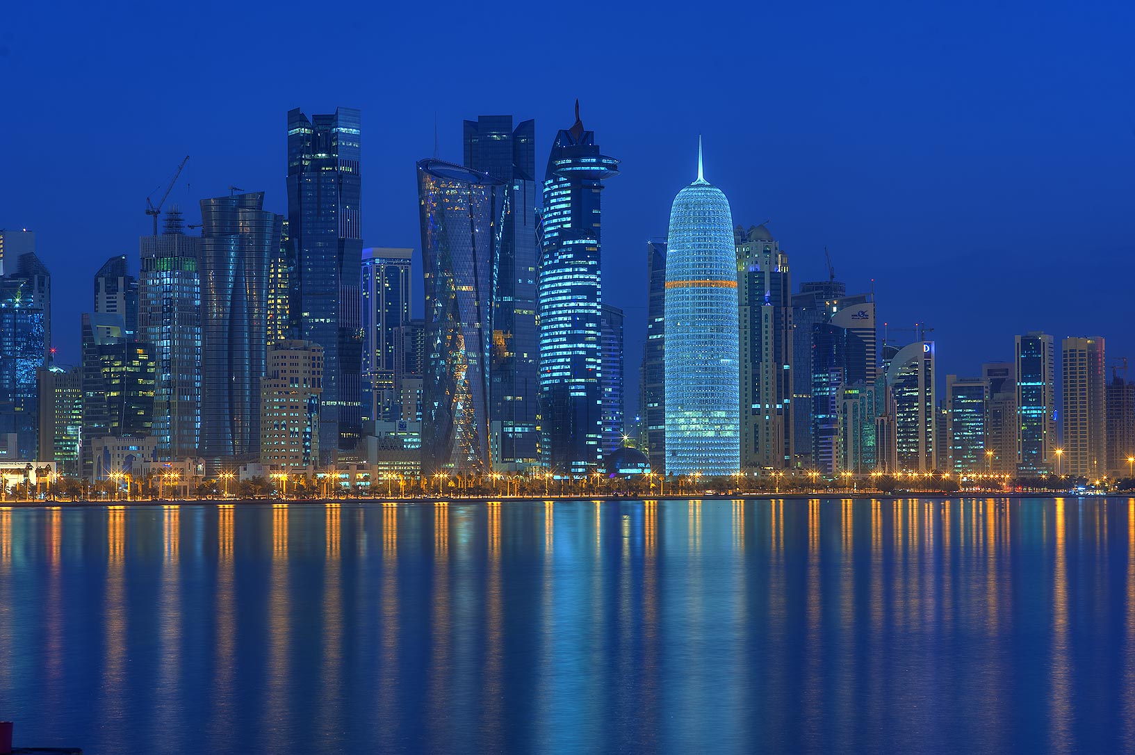 Doha West Bay skyline reflected in the water at night, the Qatar financial district that has hosted the US-Iran nuclear and Hormuz negotiations