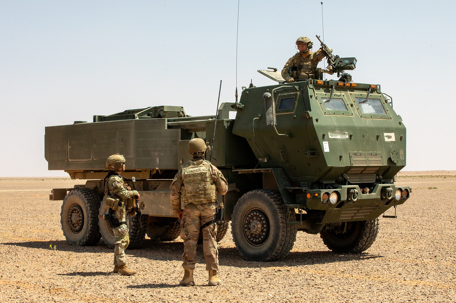 US Army M142 HIMARS launcher in desert terrain with soldiers from Florida National Guard Task Force Lightning — the same system the Wisconsin National Guard operated from northern Kuwait, able to reach Iranian military targets 300km away with a single ATACMS missile. The IRGC claimed to have destroyed two HIMARS at Camp Arifjan on July 18.