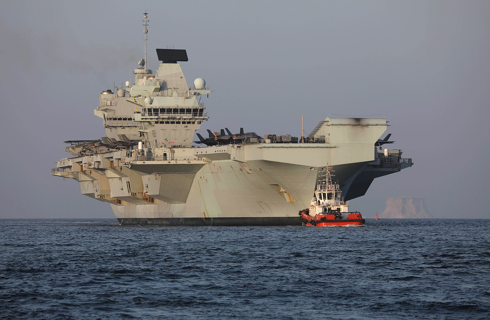 HMS Queen Elizabeth aircraft carrier with F-35B jets on deck arriving at Duqm Port, Oman, Indian Ocean