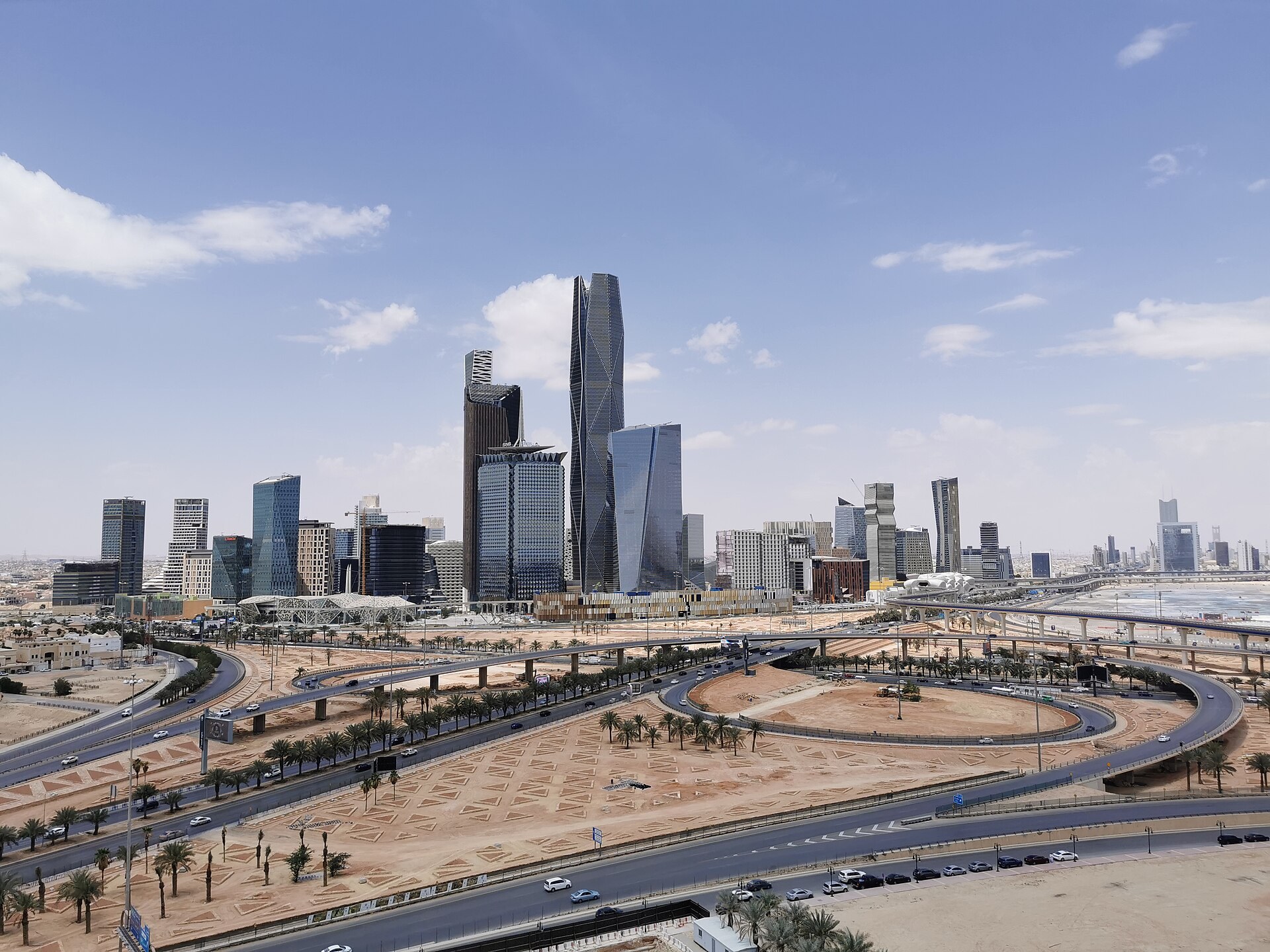 The King Abdullah Financial District in Riyadh photographed in daylight, with undeveloped land in the foreground illustrating the gap between Saudi Arabia's construction ambitions and ground reality