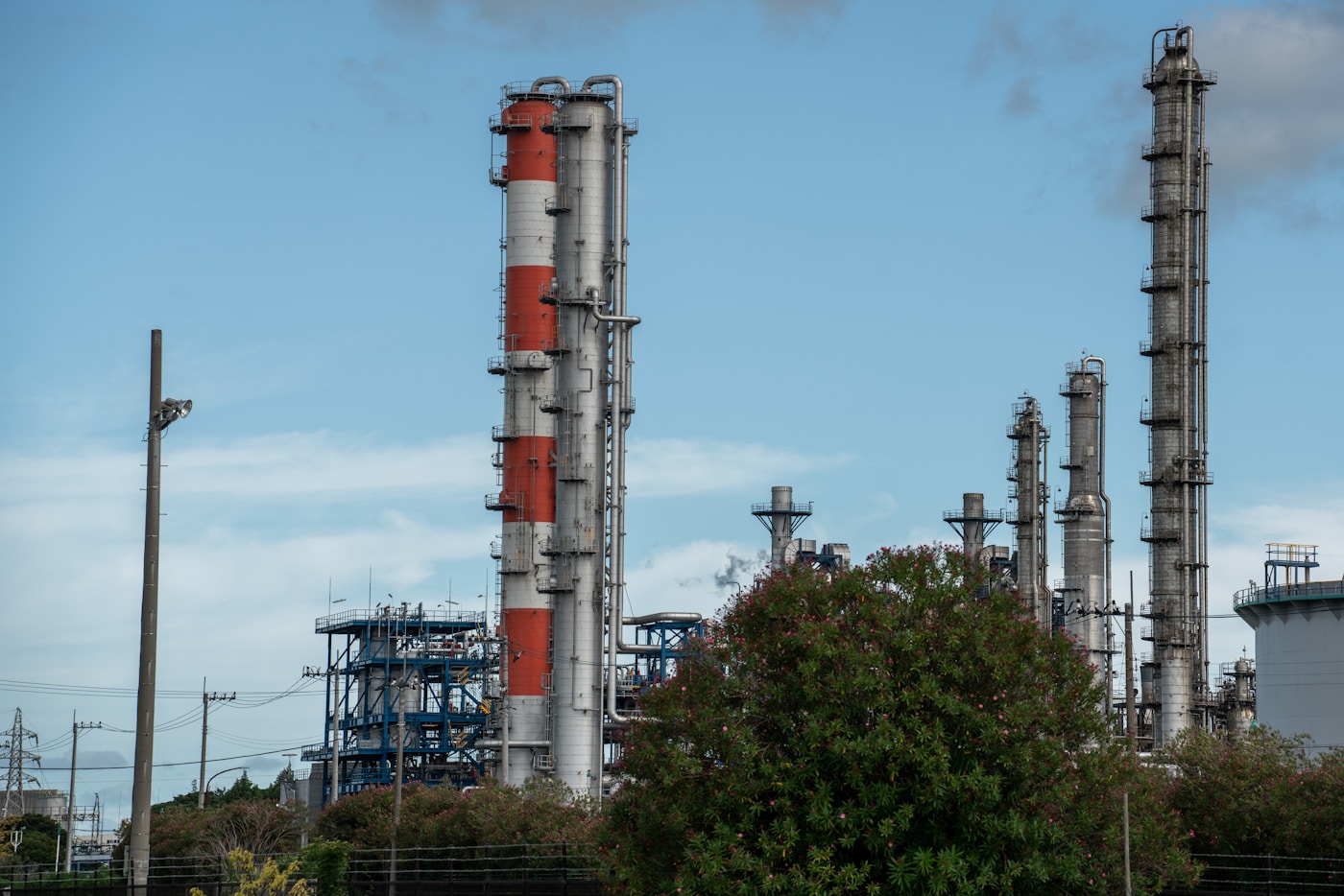 Oil refinery cracking towers and distillation columns against blue sky, representing the crude processing infrastructure that sets demand for Saudi Arab Light