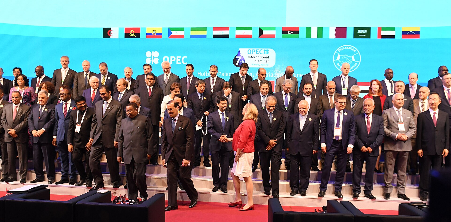OPEC member-state energy ministers and delegates gather for the 7th OPEC International Seminar in Vienna, 2018, with national flags of all member countries displayed above the stage