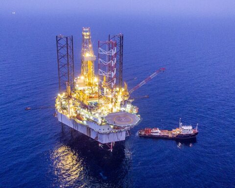 South Pars gas field offshore drilling platform in the Persian Gulf at dusk, illuminated against dark blue waters