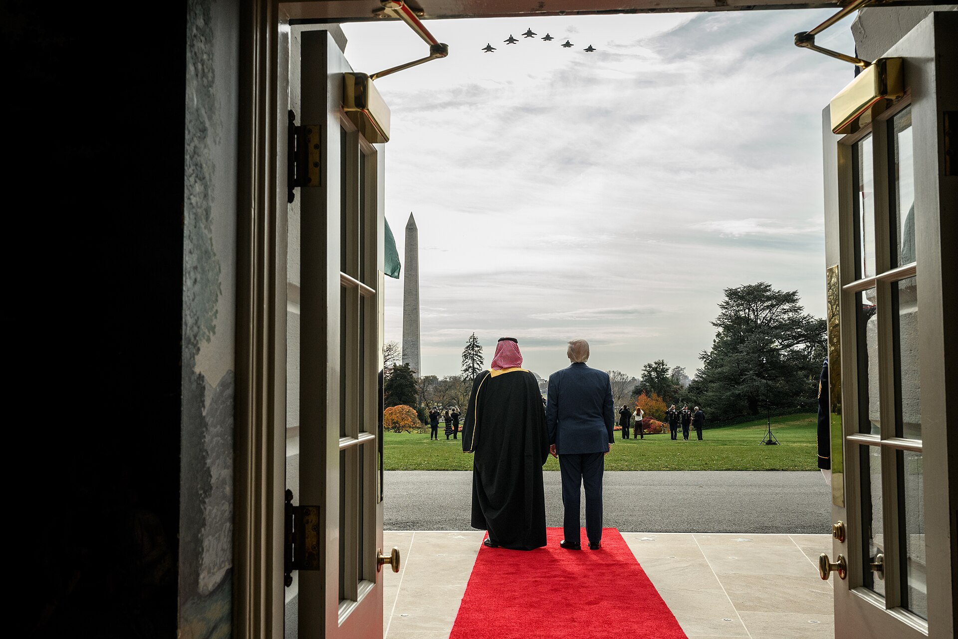 Trump and MBS on White House South Lawn red carpet with military jets flying overhead, November 2025