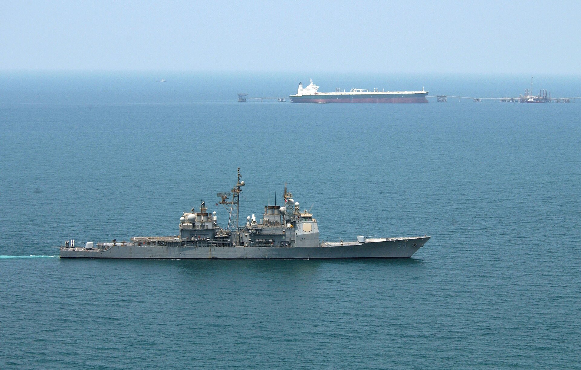 USS Chosin (CG-65) enforces an exclusionary perimeter around Saudi Aramco supertanker Abqaiq at an offshore oil terminal in the Arabian Gulf — a scene that captures the strategic stakes of Gulf crude export infrastructure