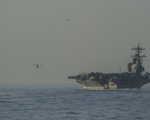 USS George H.W. Bush (CVN 77) aircraft carrier and USS Truxtun (DDG 103) guided-missile destroyer transiting the Strait of Hormuz, with MH-60R escort helicopters, US Fifth Fleet