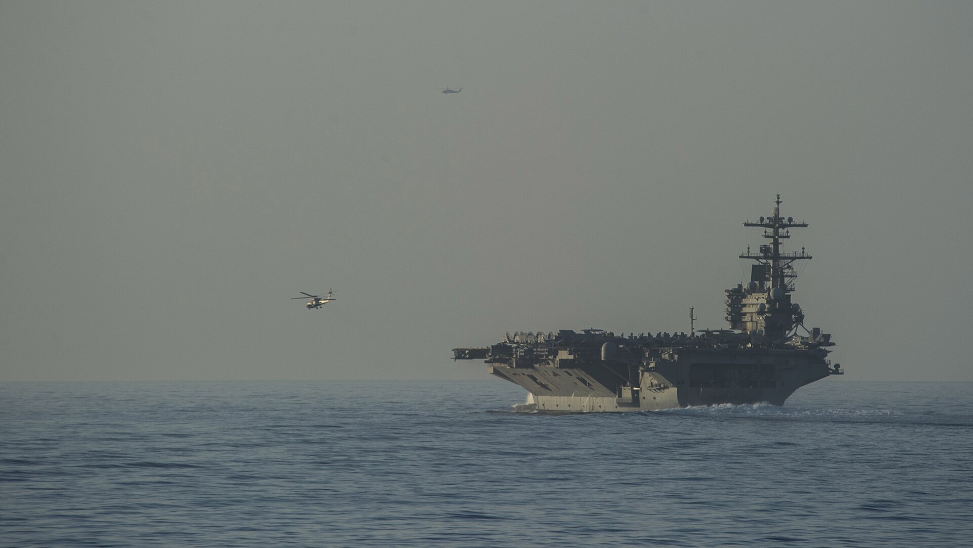 USS George H.W. Bush (CVN 77) aircraft carrier and USS Truxtun (DDG 103) guided-missile destroyer transiting the Strait of Hormuz, with MH-60R escort helicopters, US Fifth Fleet