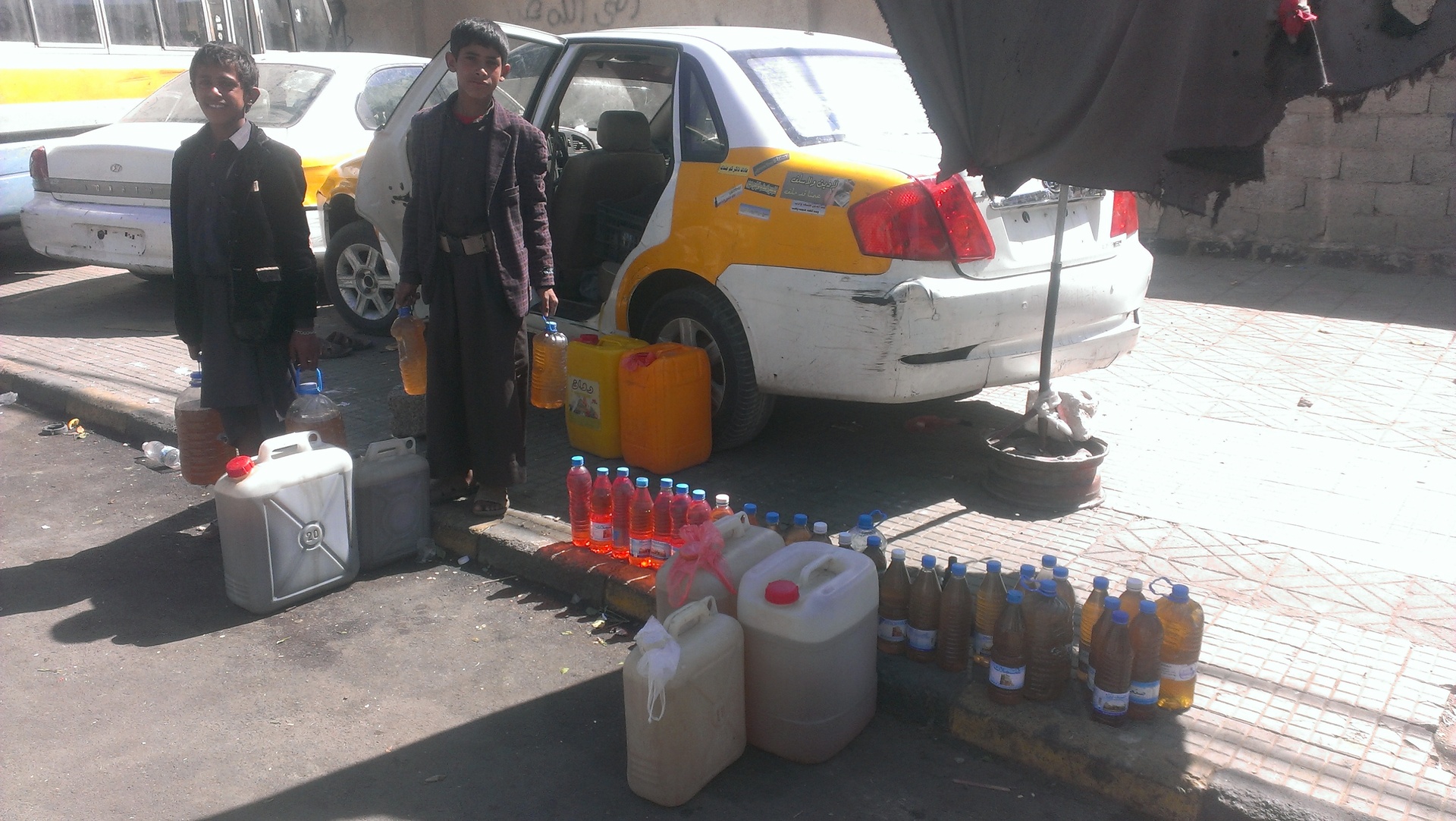 Yemeni men sell black-market fuel on a Sanaa street during the war, January 2016, illustrating the supply chain disruption that coalition strikes on Hodeidah port would intensify